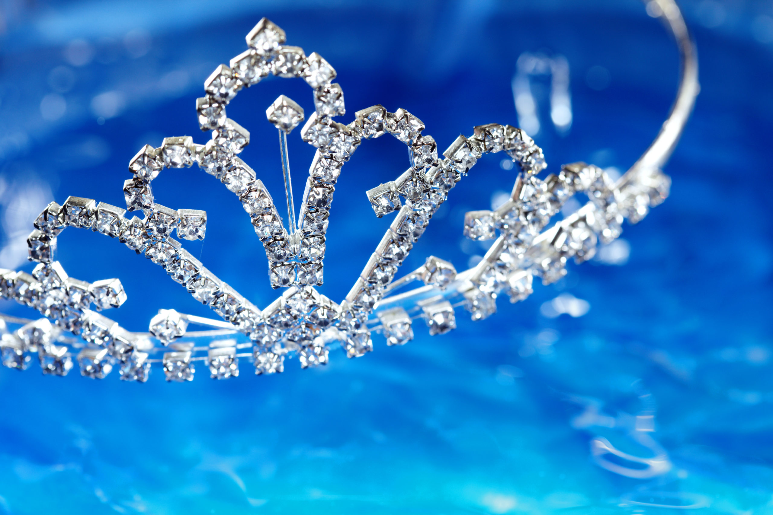 Close-up photo of the silver diadem with diamonds on a blue water background. Shallow depth of field added by macro lens for natural view